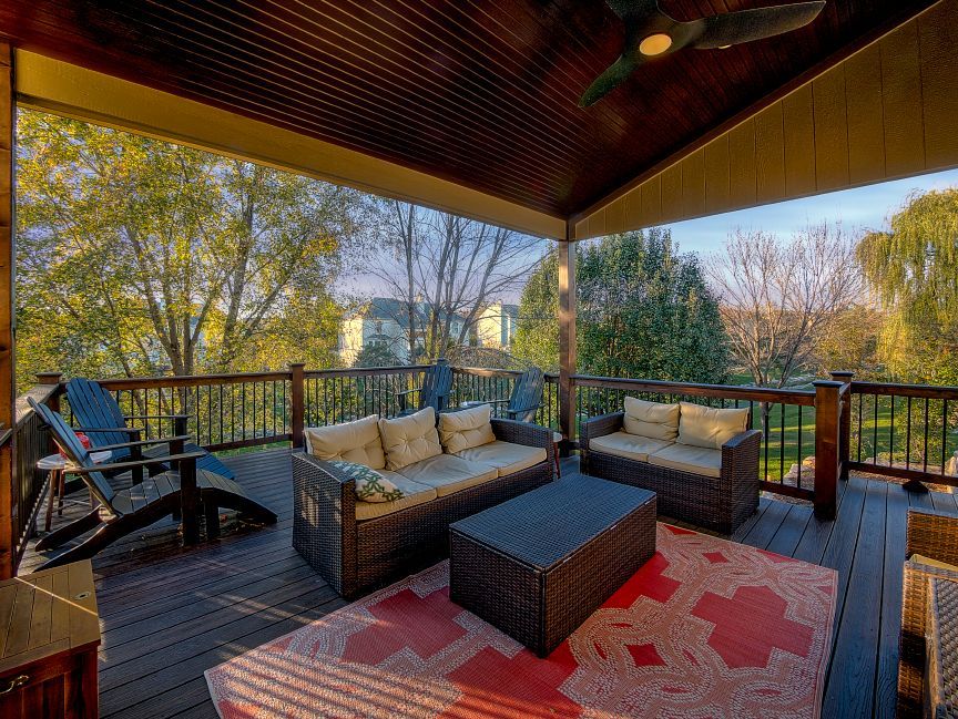 A deck with a couch , chairs , a table and a rug.
