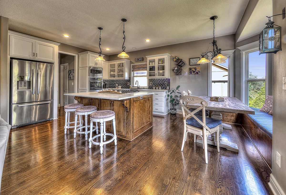A kitchen with stainless steel appliances , a large island , a table and chairs.