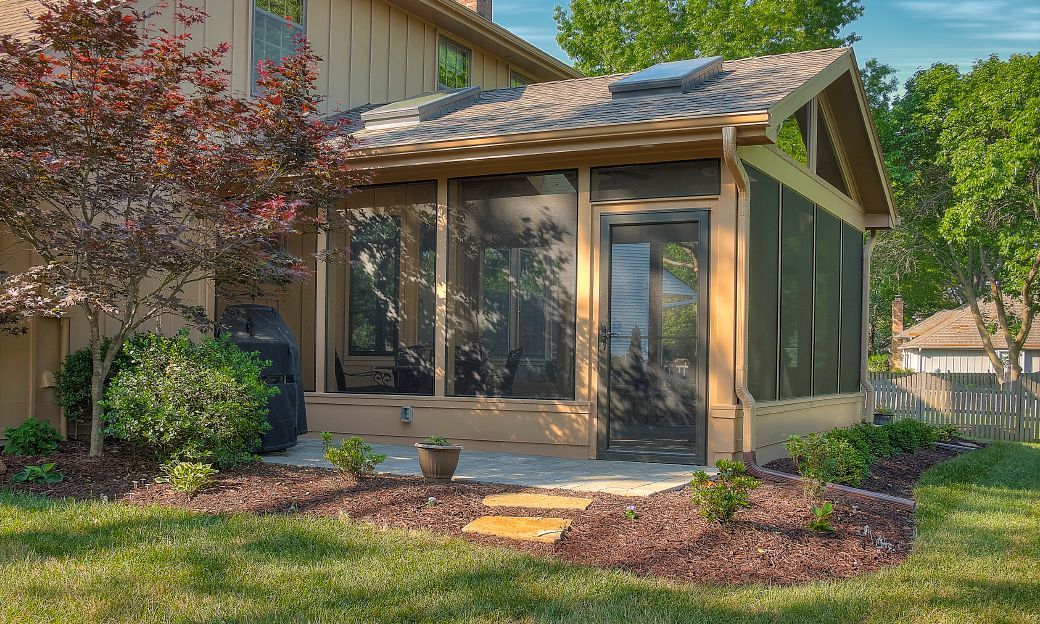 A screened in porch in the backyard of a house.