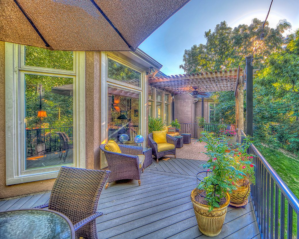 A large deck with wicker furniture and potted plants.