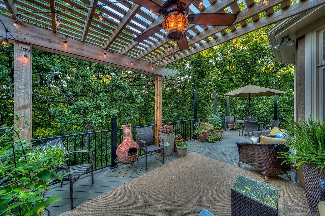 A patio with a pergola and a ceiling fan.