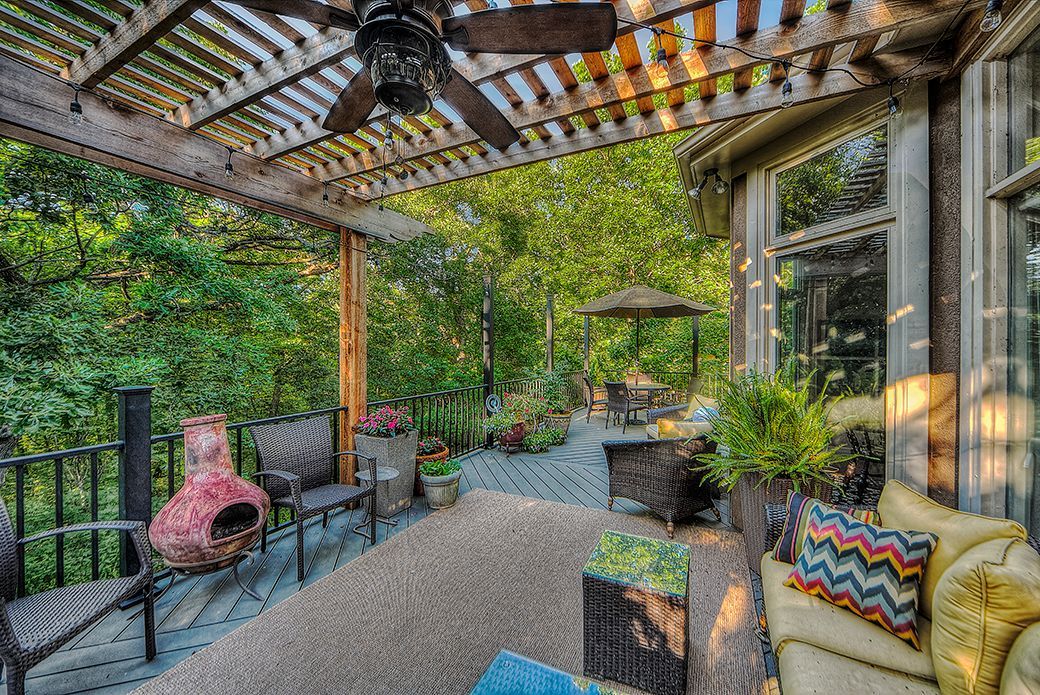 A patio with a pergola and a ceiling fan.