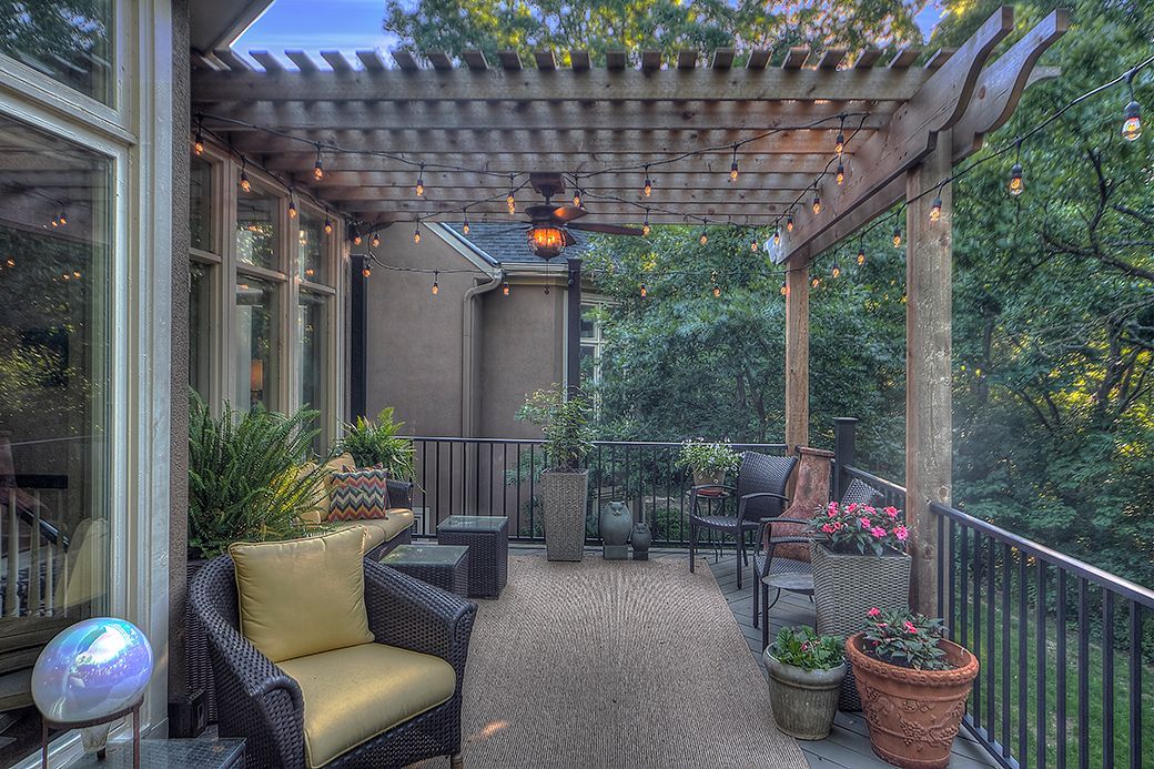 A patio with a pergola , chairs , tables and potted plants.