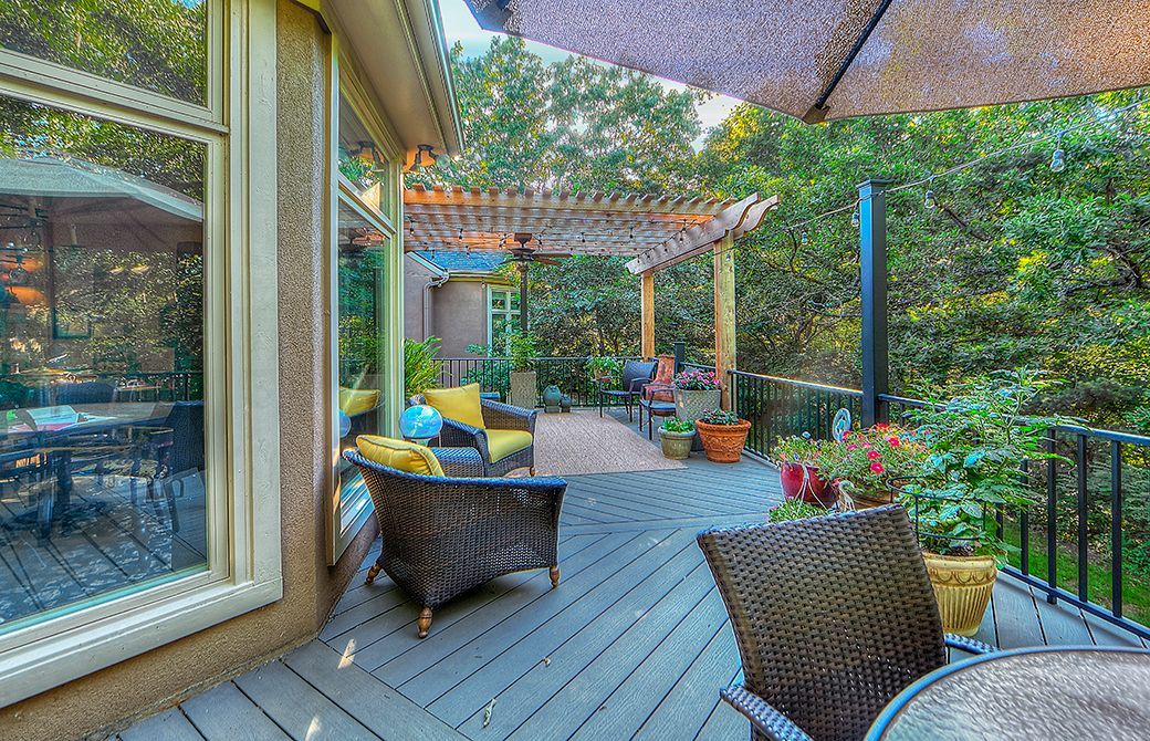 A patio with a table , chairs , umbrellas and a pergola.