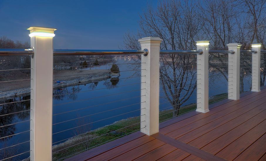 A wooden deck with a stainless steel railing overlooking a body of water.
