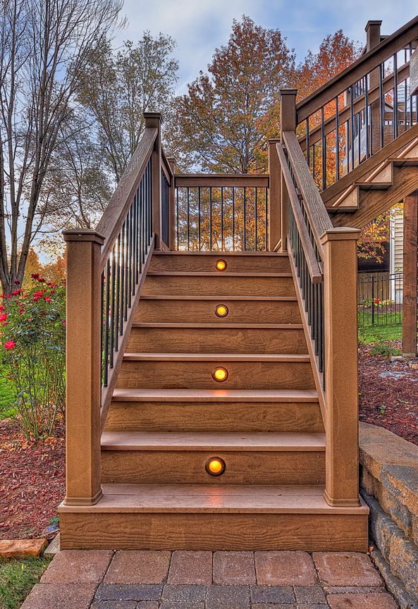 A set of stairs leading up to a deck with lights on the steps.