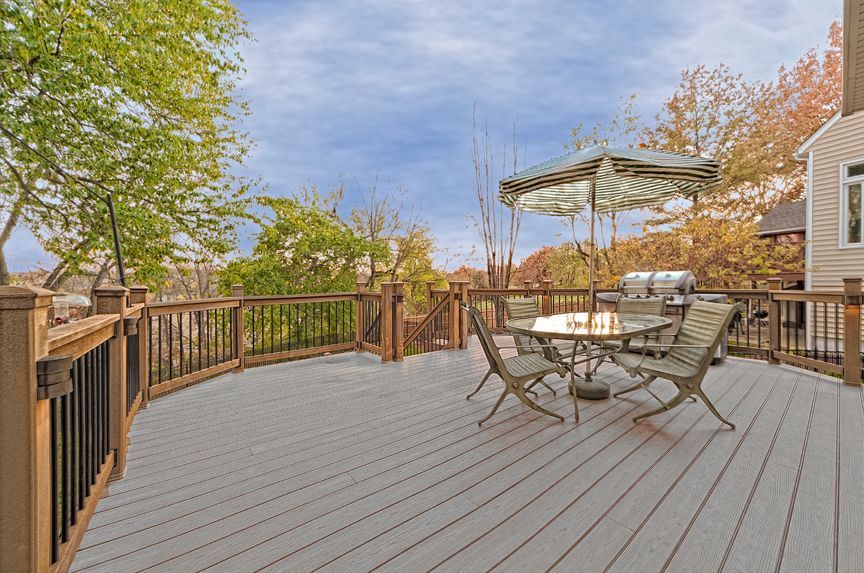 A large deck with a table and chairs and an umbrella.