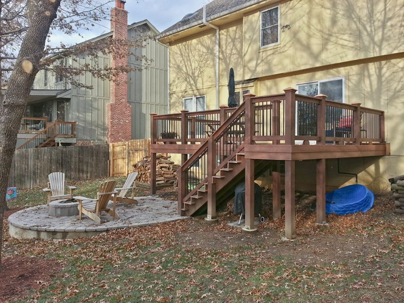 A wooden deck with stairs and a fire pit in the backyard of a house.