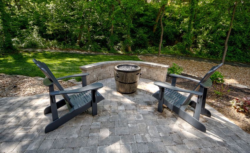 Two chairs are sitting on a patio next to a fire pit.