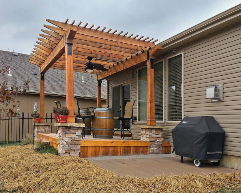 A house with a pergola and a grill in the backyard