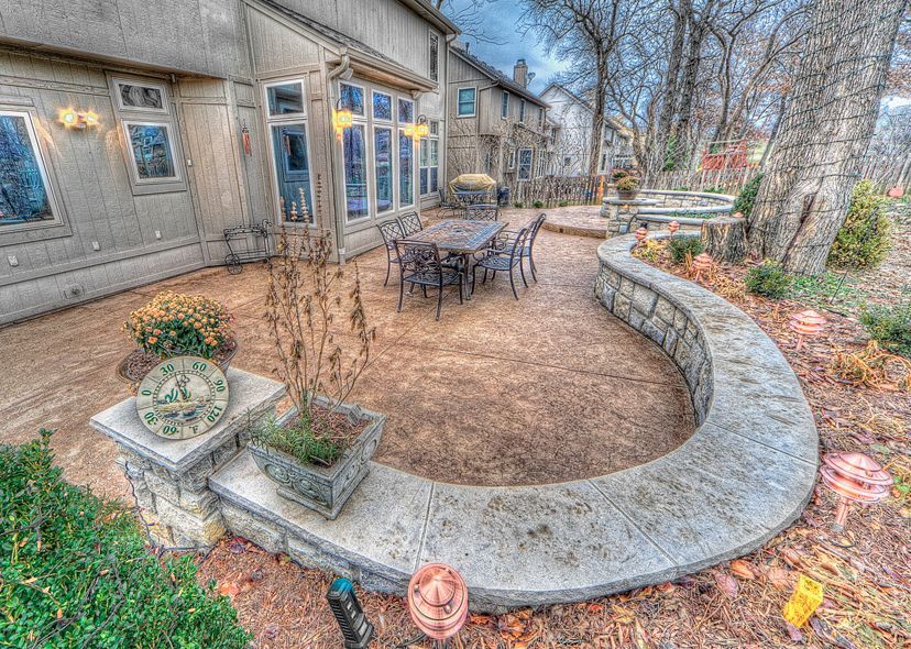 A patio with a table and chairs and a stone wall surrounding it.
