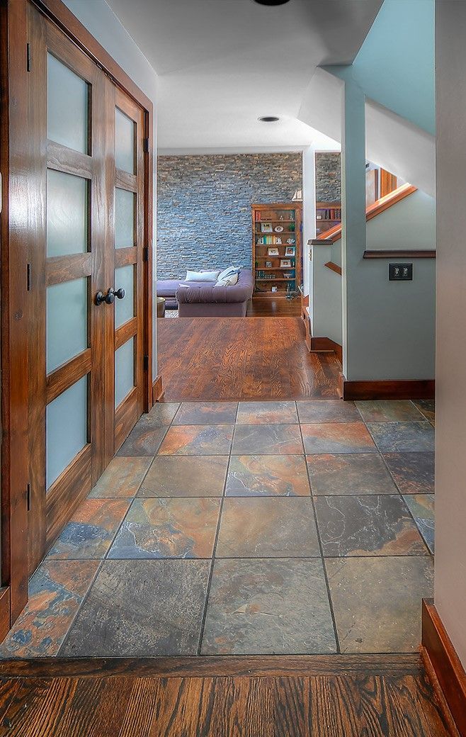 A hallway with tile floors and wooden doors leading to a living room.