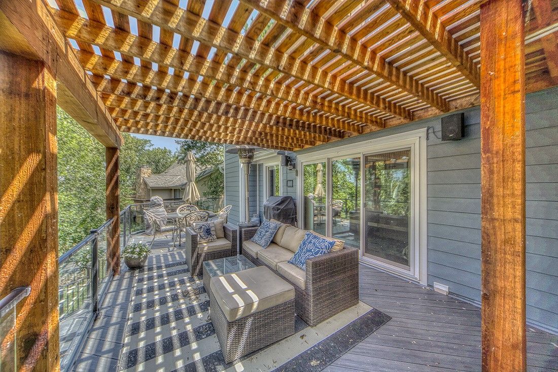 A wooden pergola over a patio with a couch and chairs.
