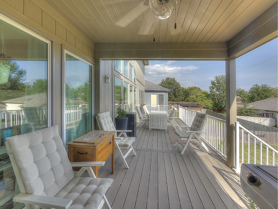 A porch with chairs , a table and a ceiling fan