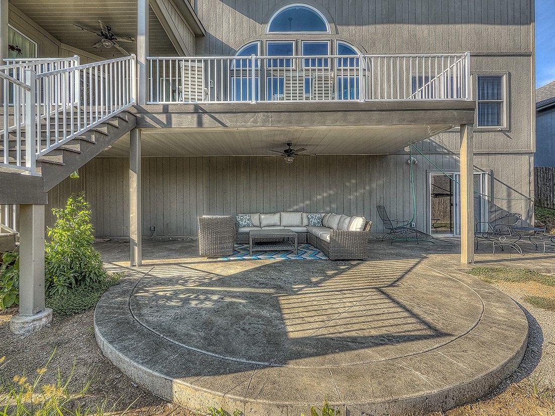 The back of a house with a large deck and stairs leading up to it.