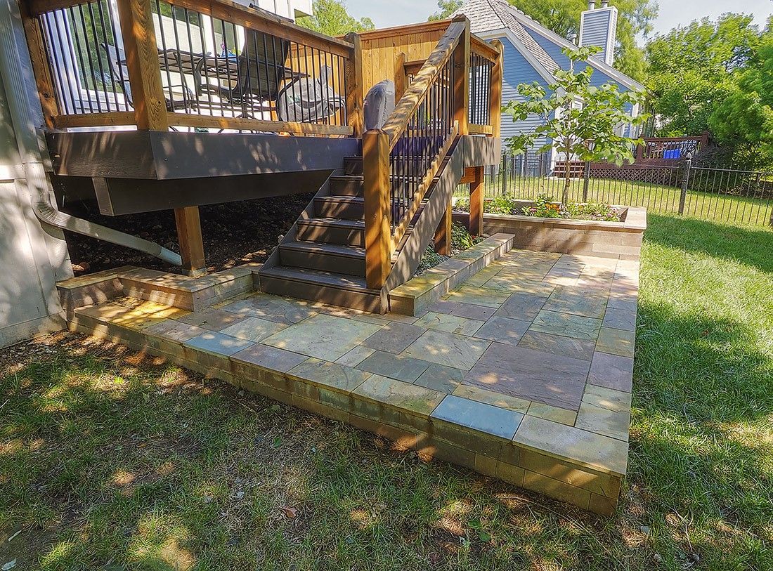 A wooden deck with stairs leading up to it in a backyard.
