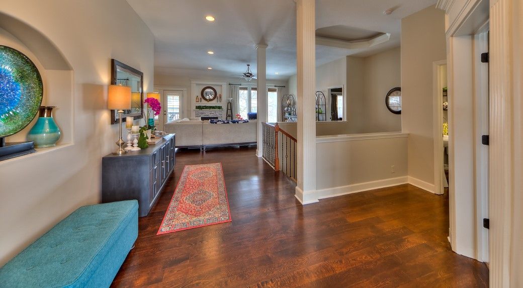 A hallway in a house with hardwood floors and a blue bench.