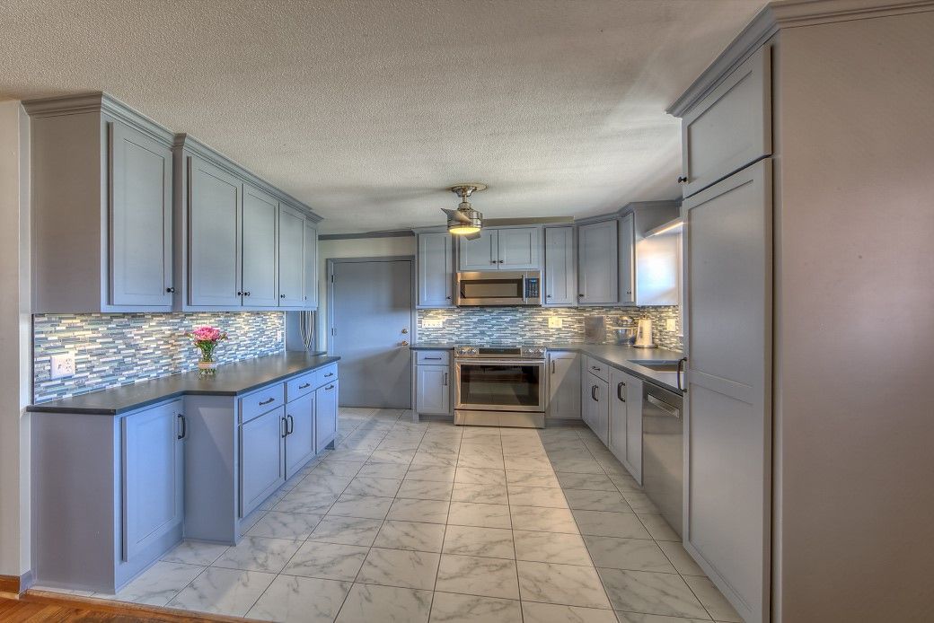 A kitchen with gray cabinets and stainless steel appliances