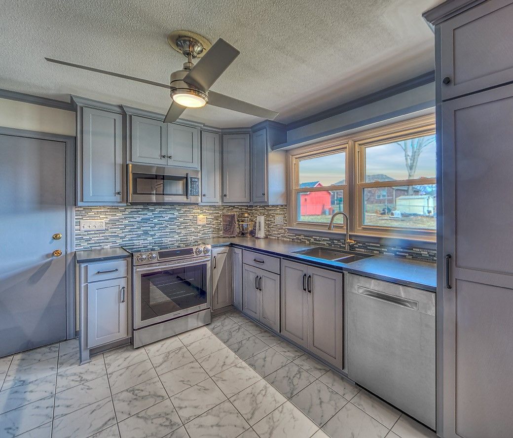 A kitchen with gray cabinets and a ceiling fan