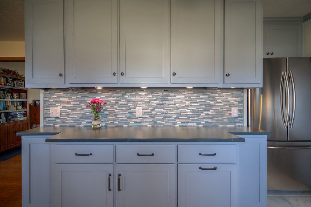 A kitchen with white cabinets and a stainless steel refrigerator.