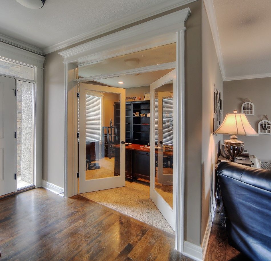 A living room with a black leather couch and a lamp