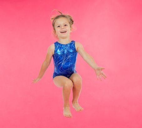 Young girl, in leotard, jumping and smiling
