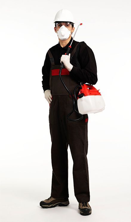Un hombre que lleva un casco y un mono sostiene un rociador.