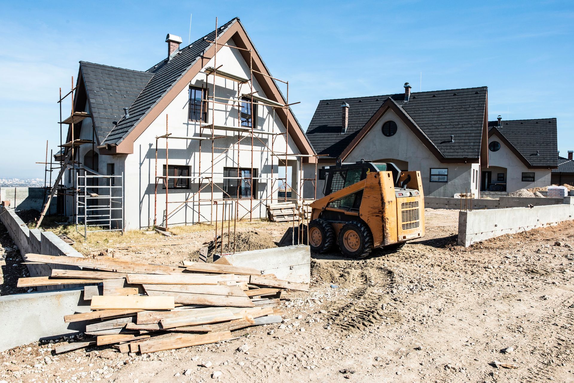 A construction site with a house under construction and a bulldozer in front of it.