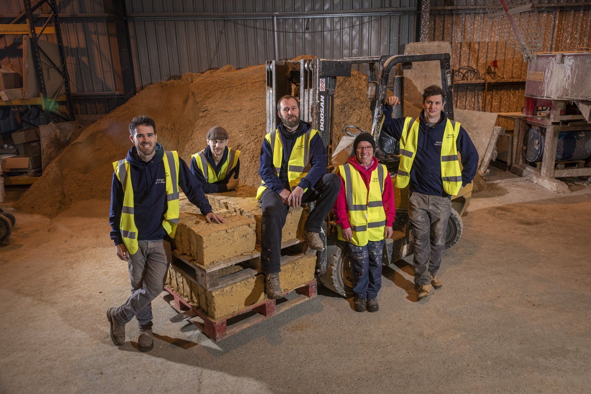 A group of construction workers are posing for a picture in a warehouse.