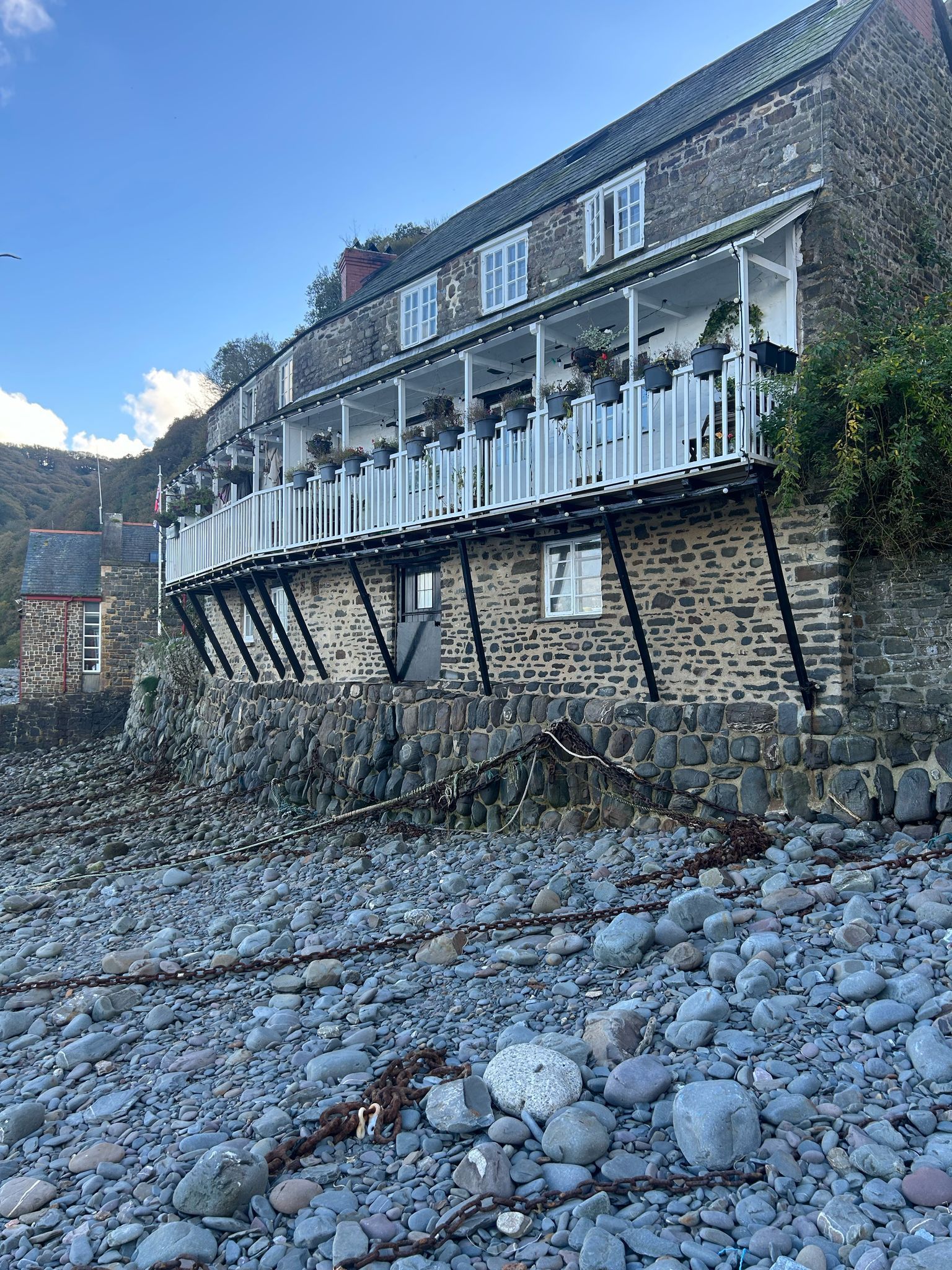 A large brick building is sitting on top of a rocky beach.