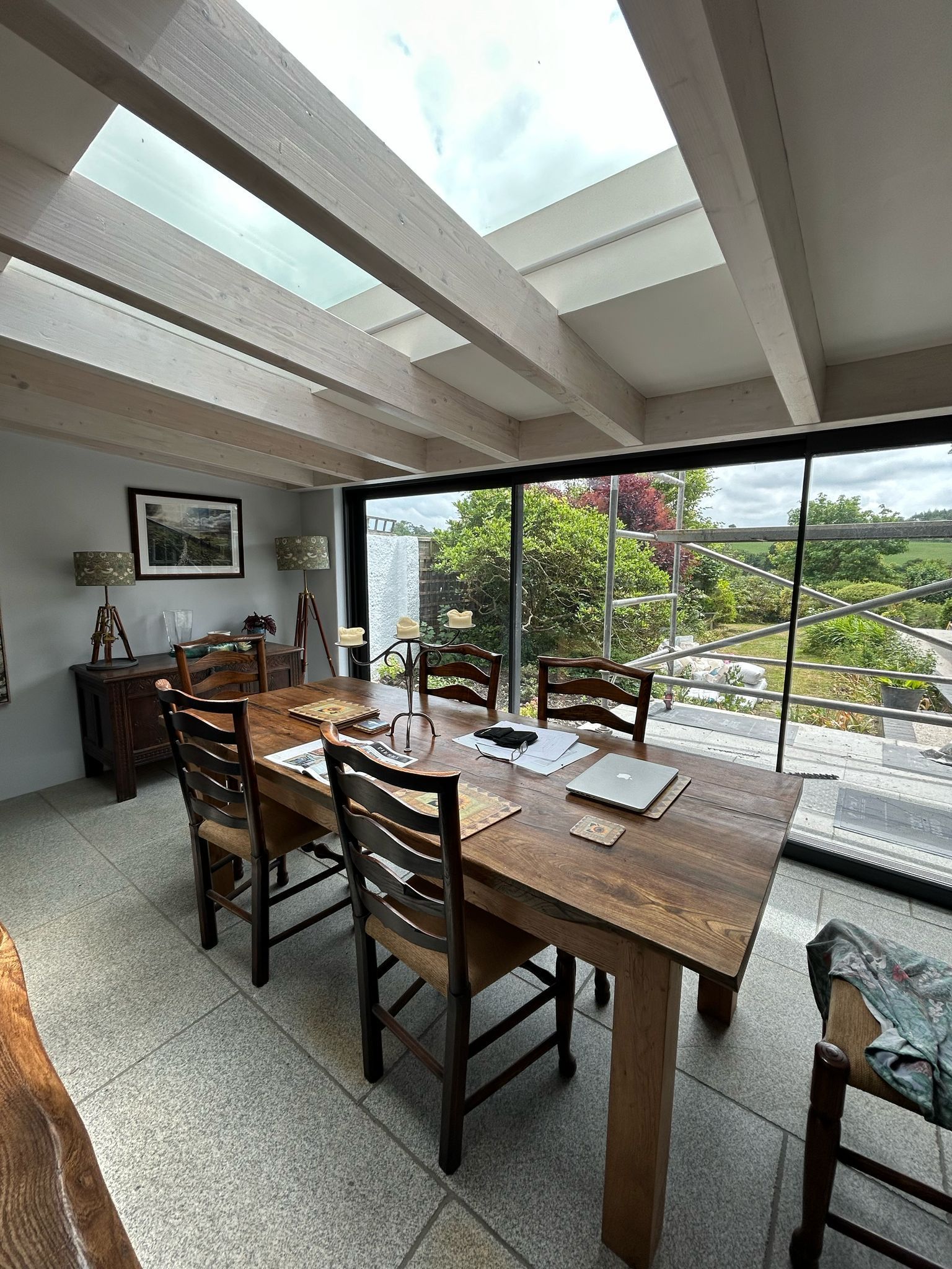 A dining room with a wooden table and chairs and a skylight.