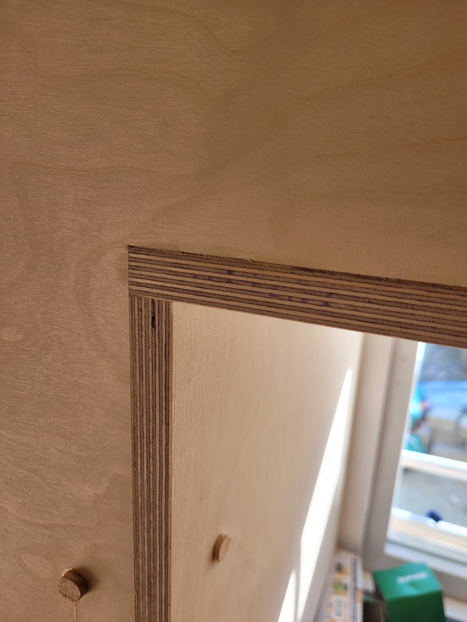 A close up of a piece of wood with a window in the background.