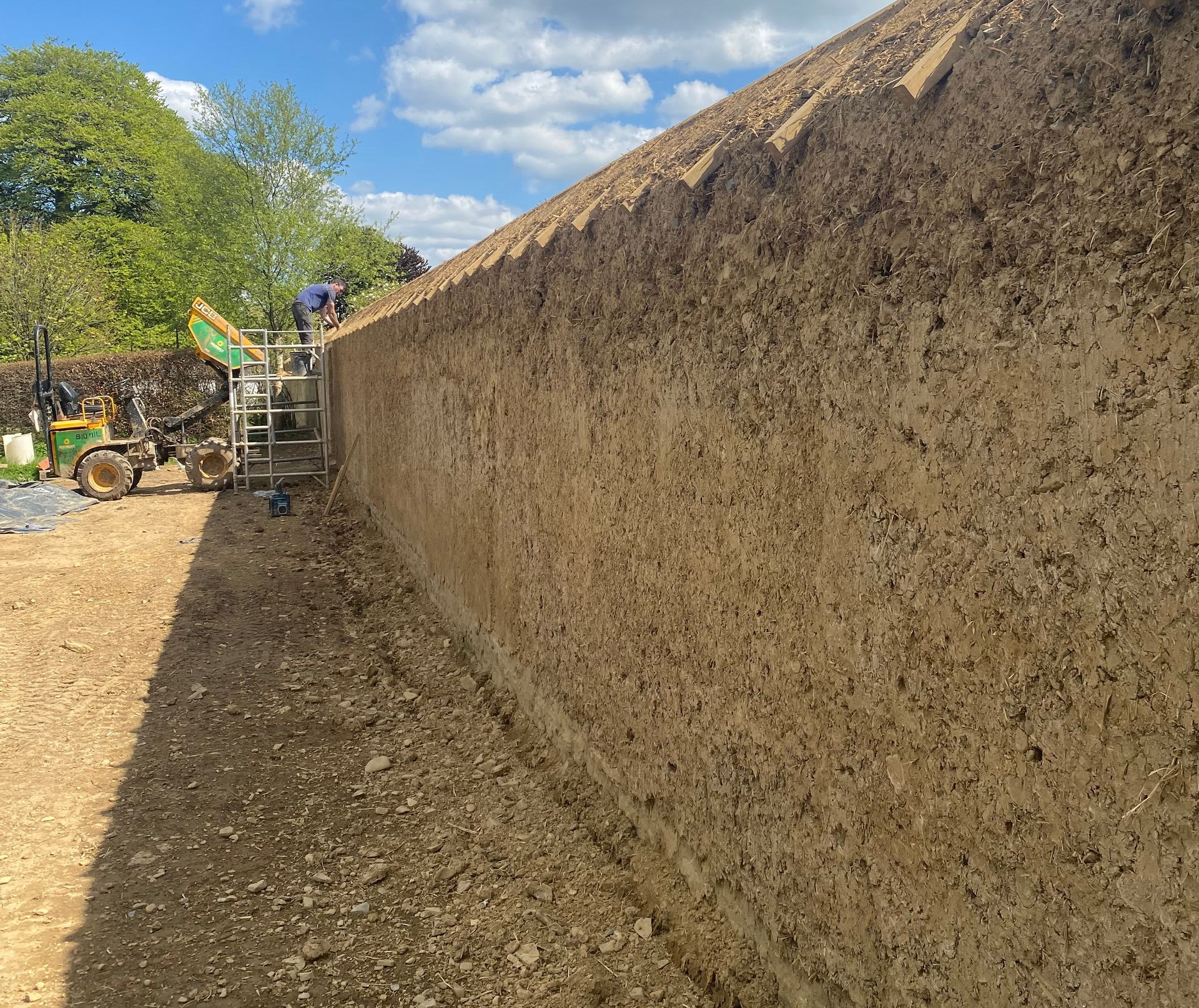 A large yellow house with a red roof is sitting on top of a lush green field.