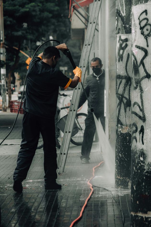 A man is cleaning a wall with a high pressure washer.