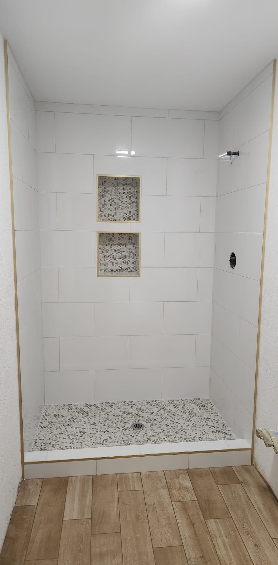 A bathroom with a walk in shower and a wooden floor.