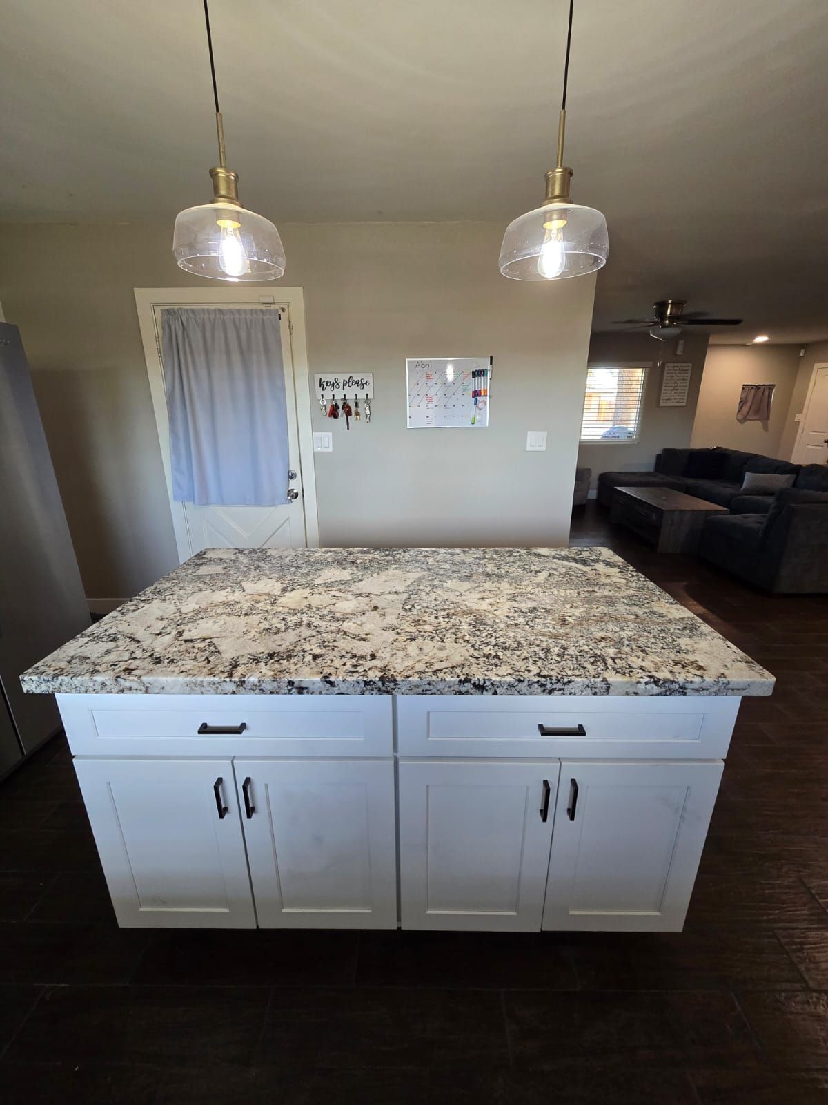 A kitchen with a large island and two pendant lights hanging from the ceiling.