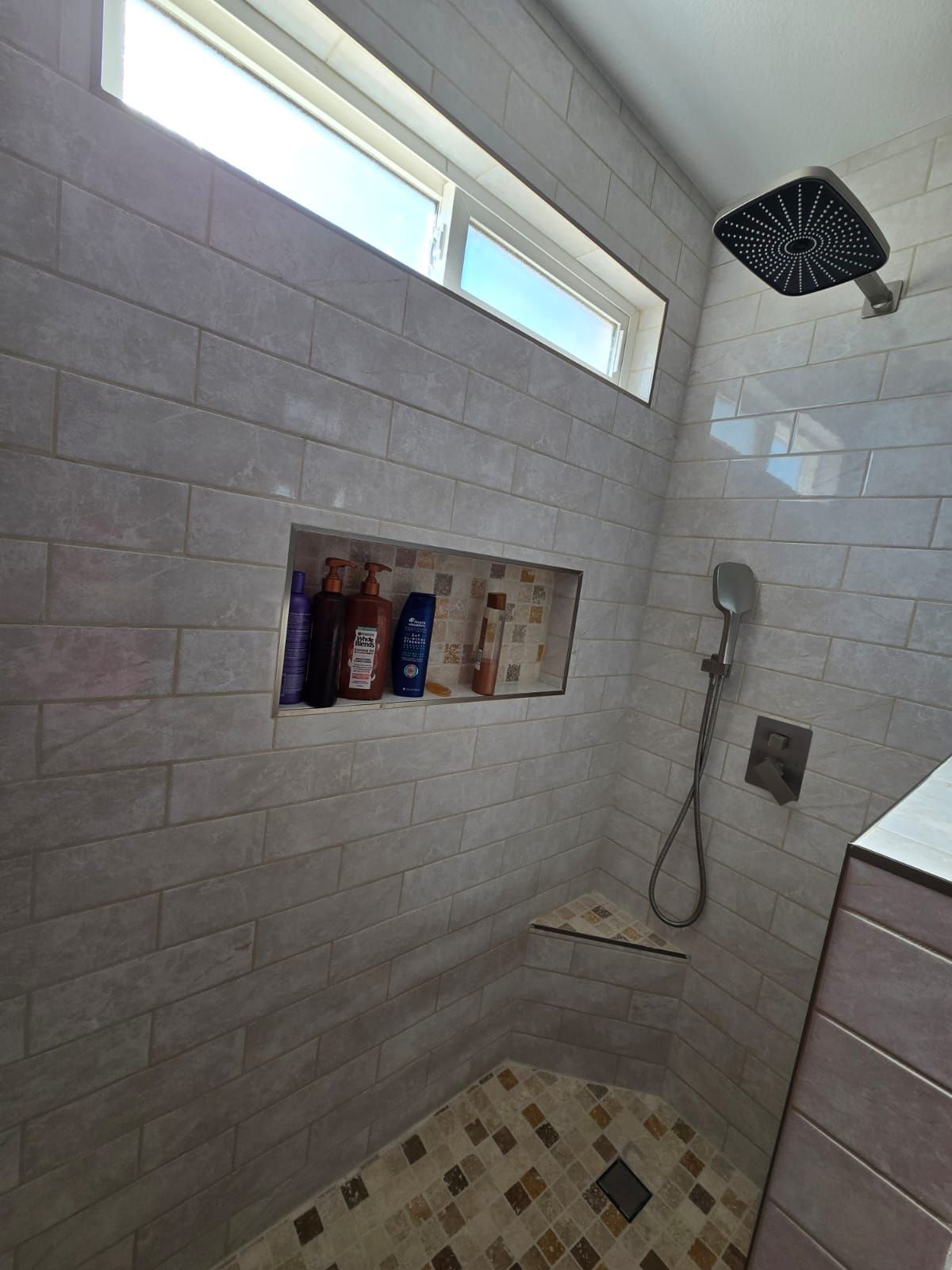 A shower with a window and a shower head.