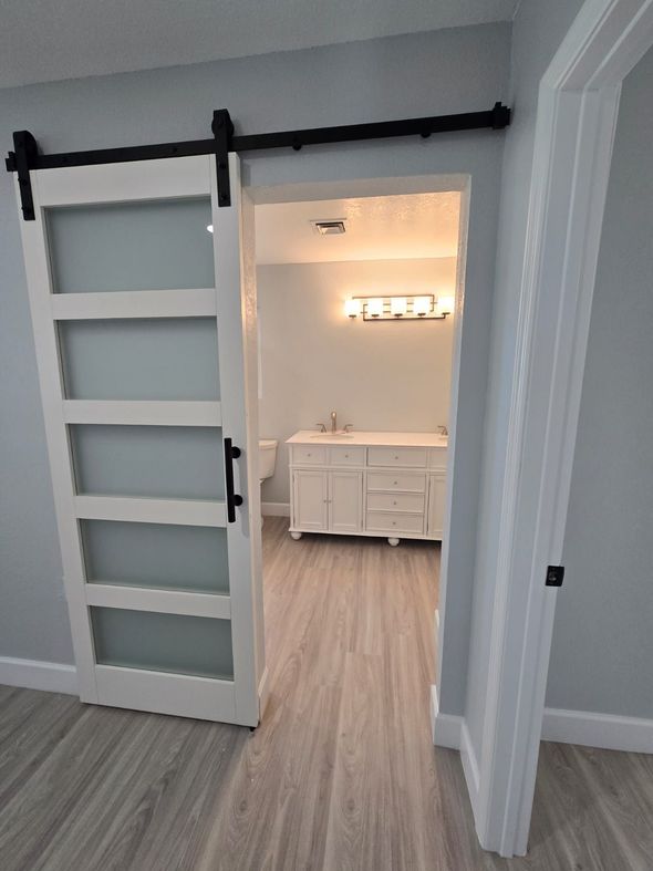 A bathroom with a sliding barn door leading to it.