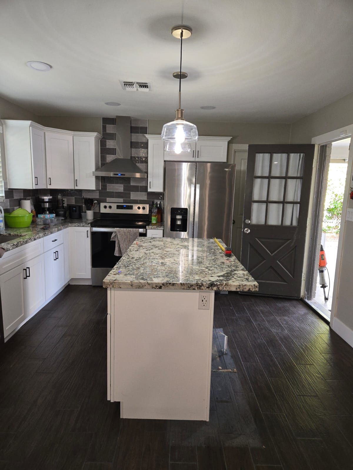 A kitchen with a large island in the middle and stainless steel appliances.