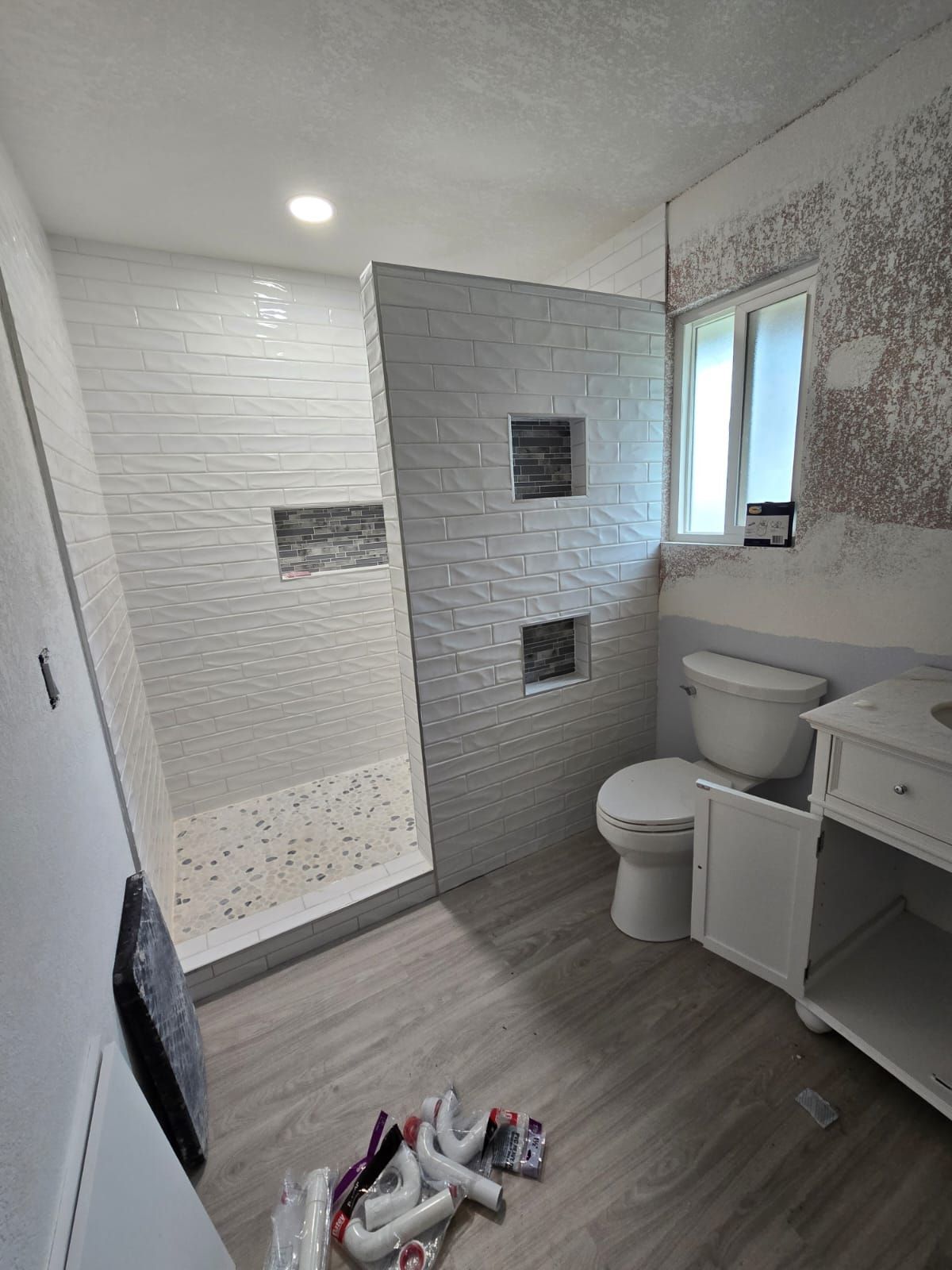 A bathroom with a toilet , sink , shower and window.