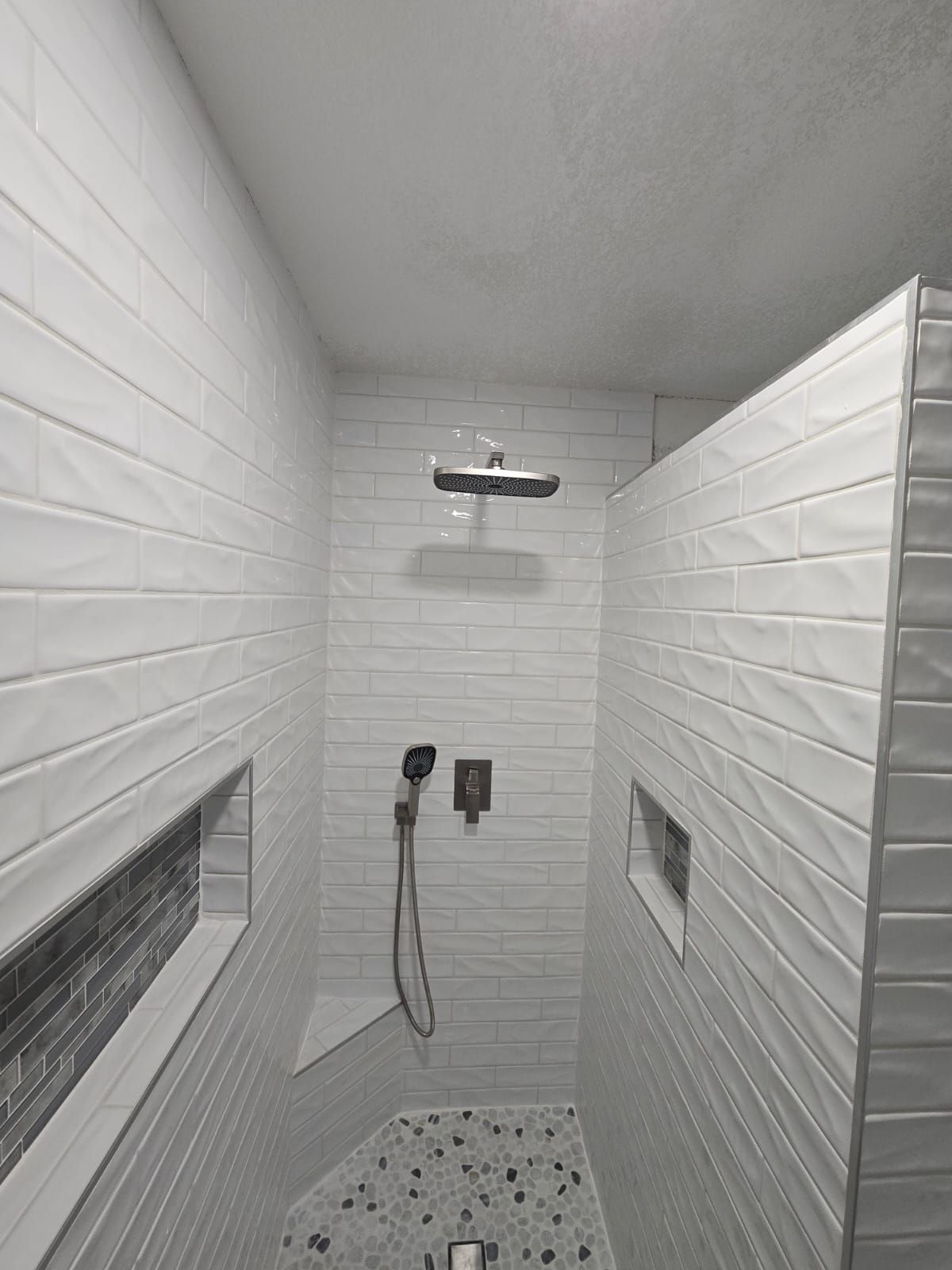 A shower with white tiles and a shower head.