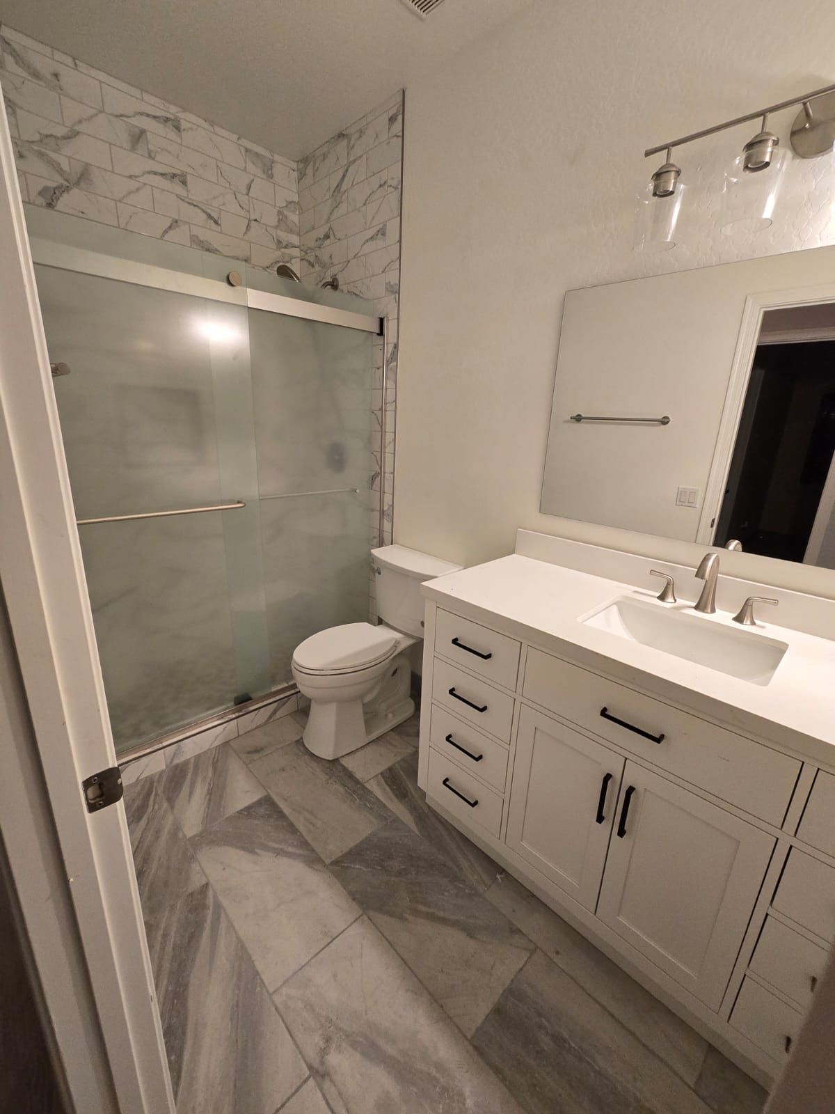 A bathroom with a toilet , sink , mirror and shower.