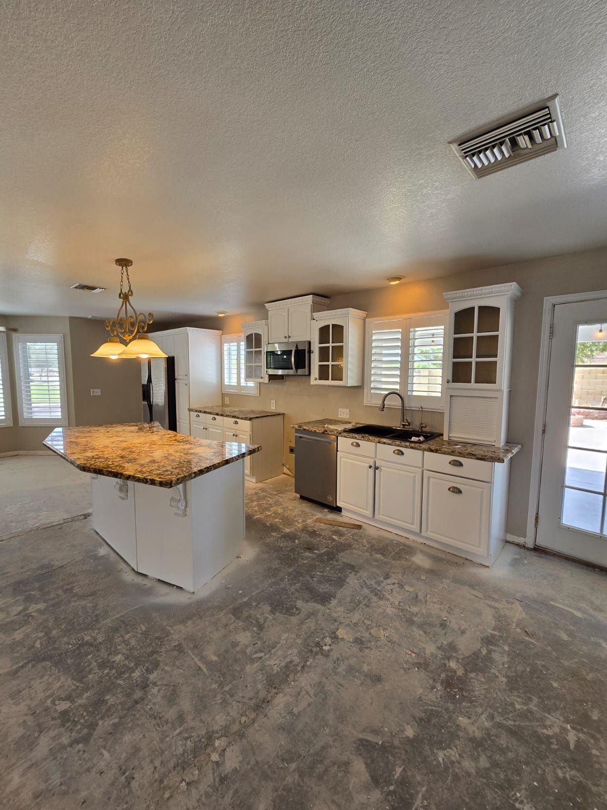 An empty kitchen with white cabinets and granite counter tops.