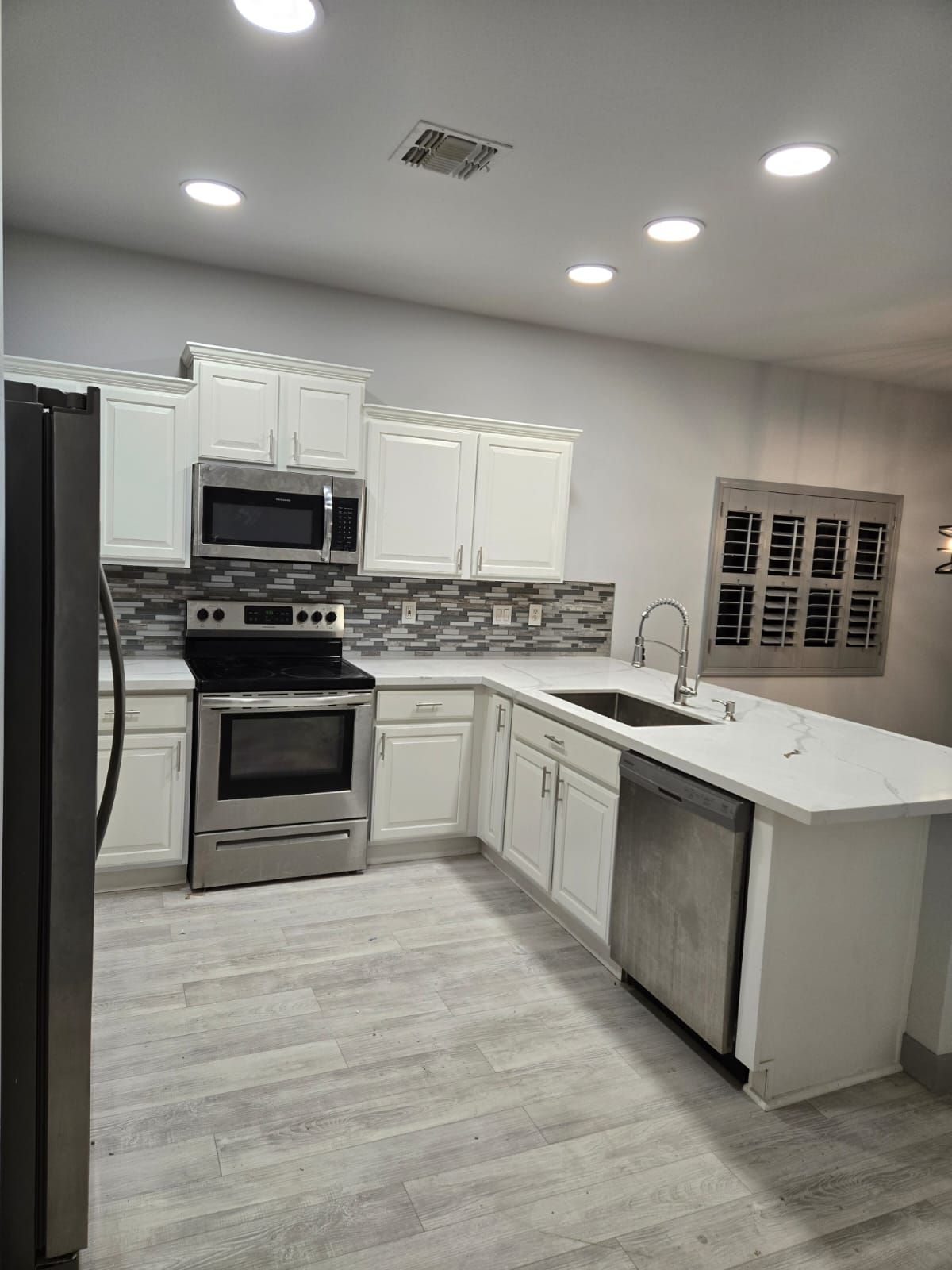 A kitchen with stainless steel appliances and white cabinets.
