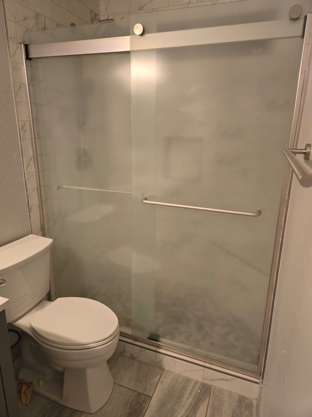 A bathroom with a toilet and a sliding glass shower door.