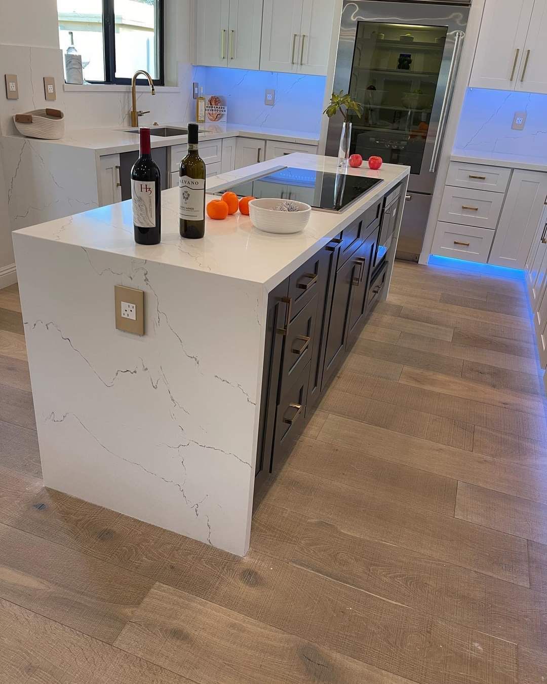 A kitchen with a large island and two bottles of wine on it.