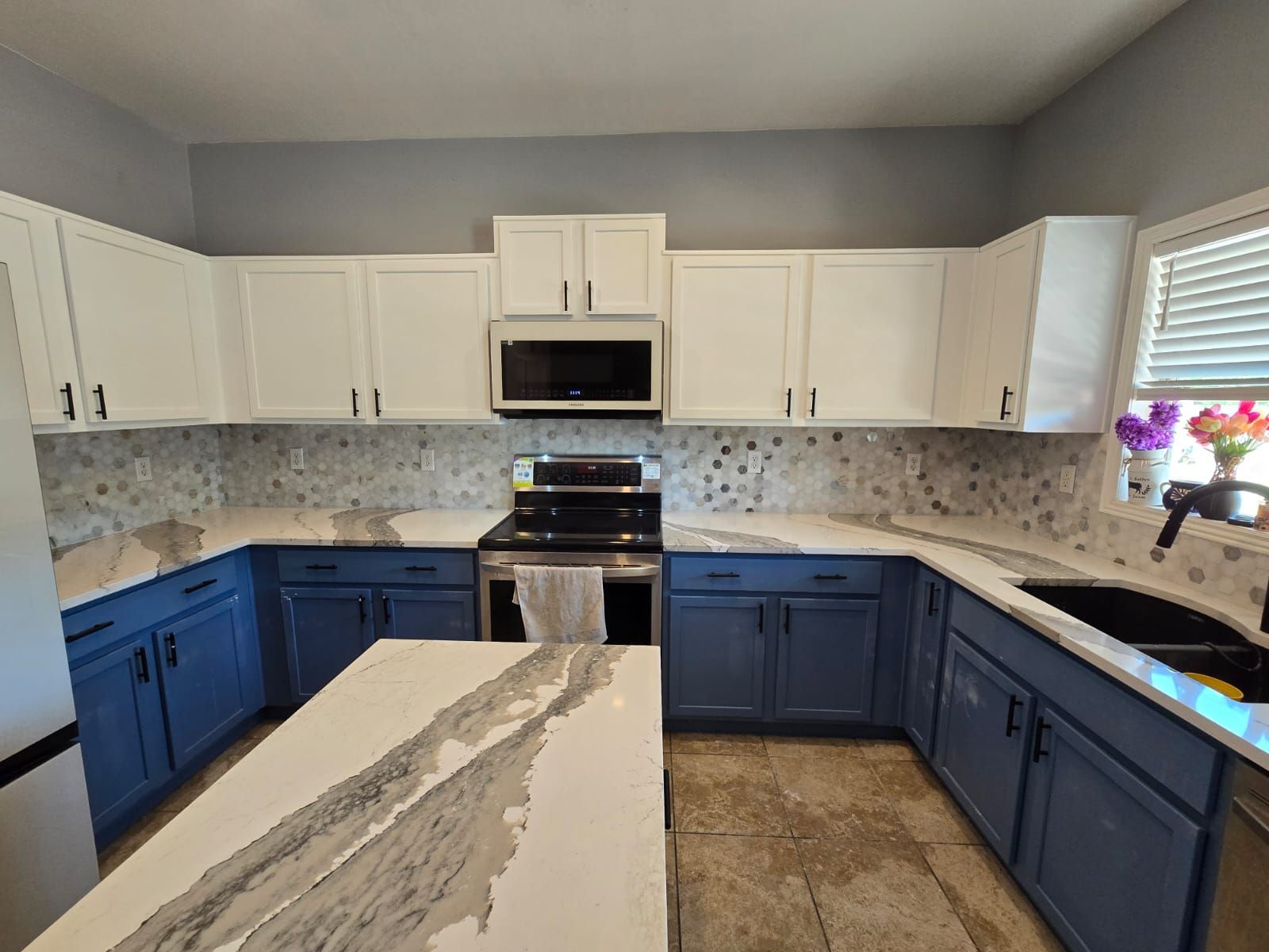 A kitchen with blue cabinets and white counter tops.