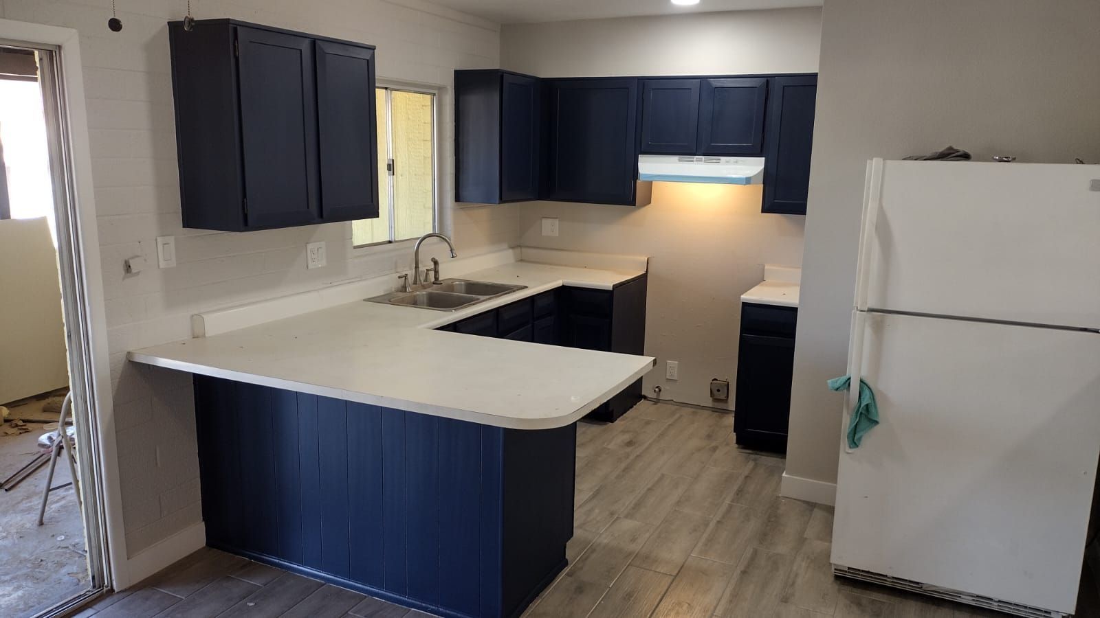 A kitchen with blue cabinets and a white refrigerator.