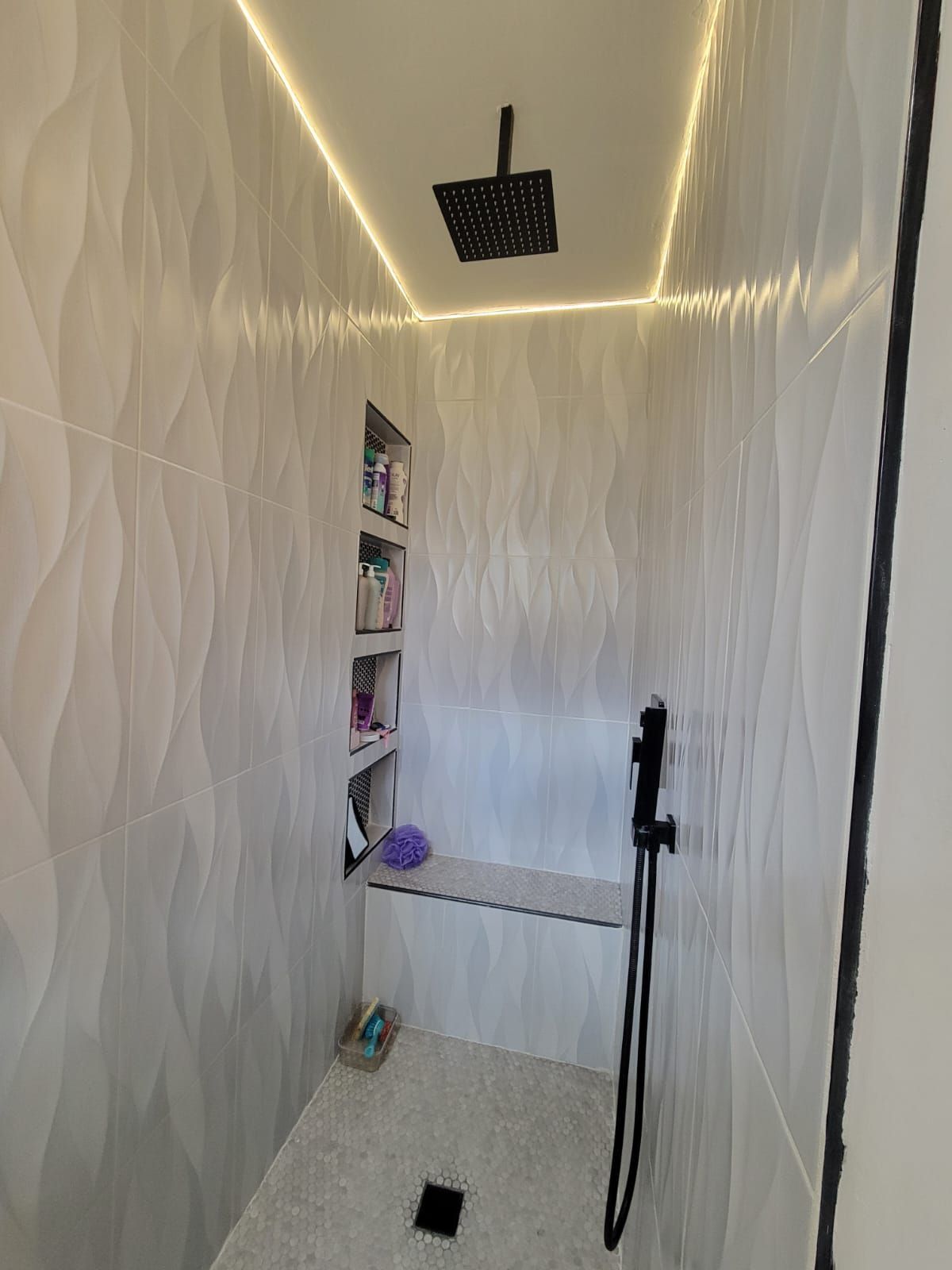 A bathroom with a shower head and a bench.