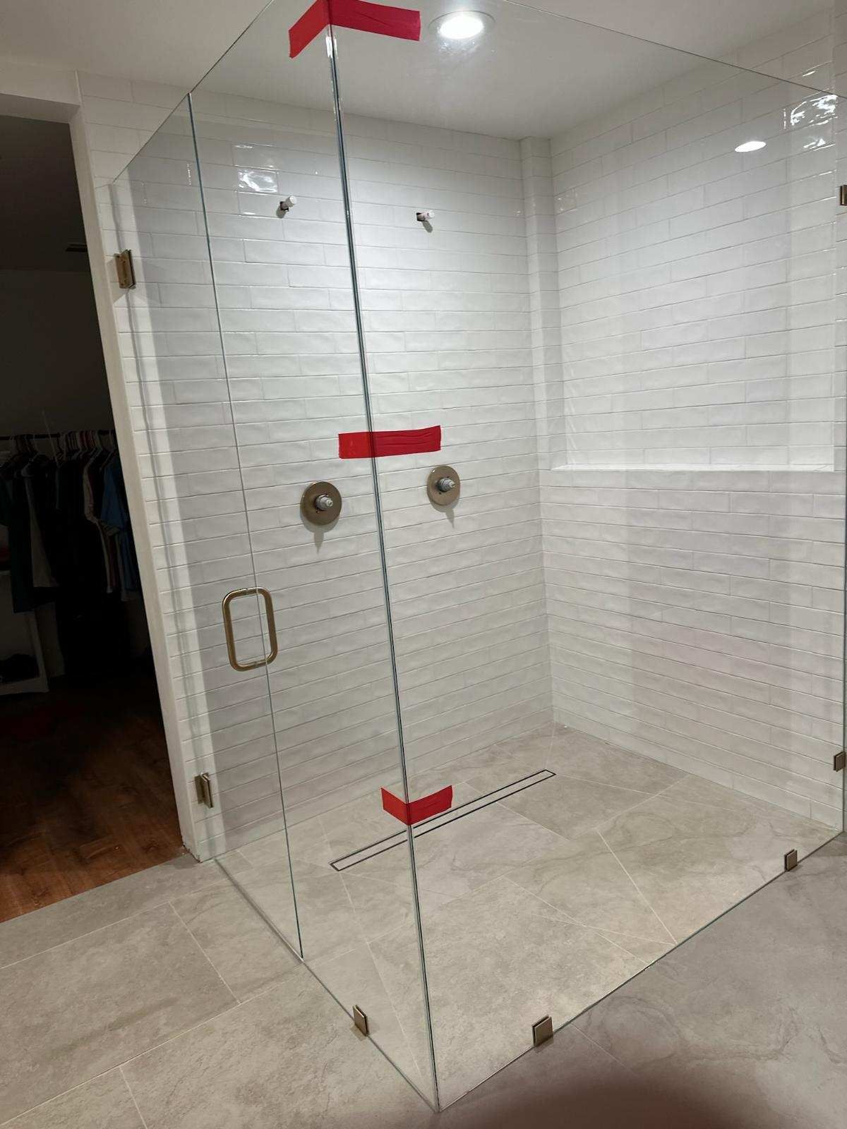 A bathroom with a walk in shower with a glass door.